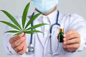 medical-doctor-holding-cannabis-leaf-bottle-cannabis-oil-white-wall