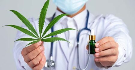 medical-doctor-holding-cannabis-leaf-bottle-cannabis-oil-white-wall